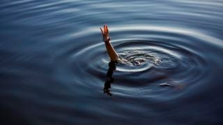 A drowning hand reaching out of a body of water