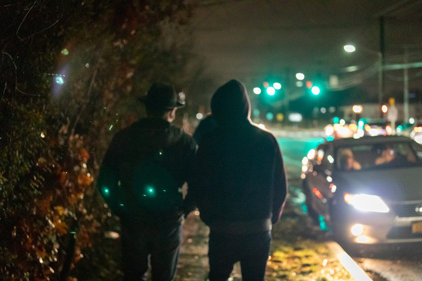 two men walk along a city street at night
