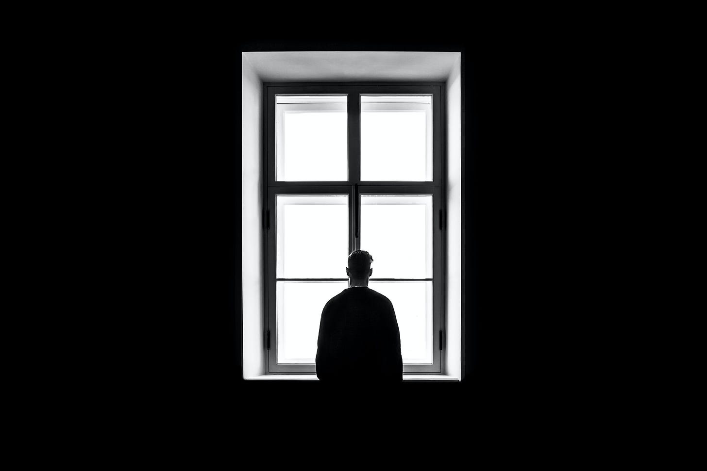 Photograph of a man peering out of a window. Photography by Sasha Freemind.