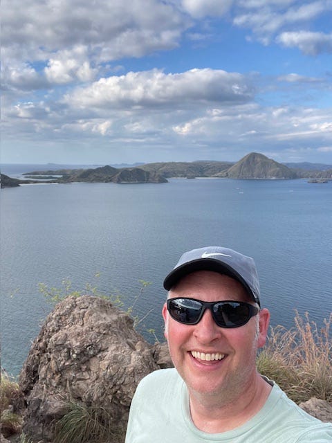 Dr. Dave at the top of an island mountain with seas and smaller islands in the background Dr. Dave at the top of an island mountain with seas and smaller islands in the background