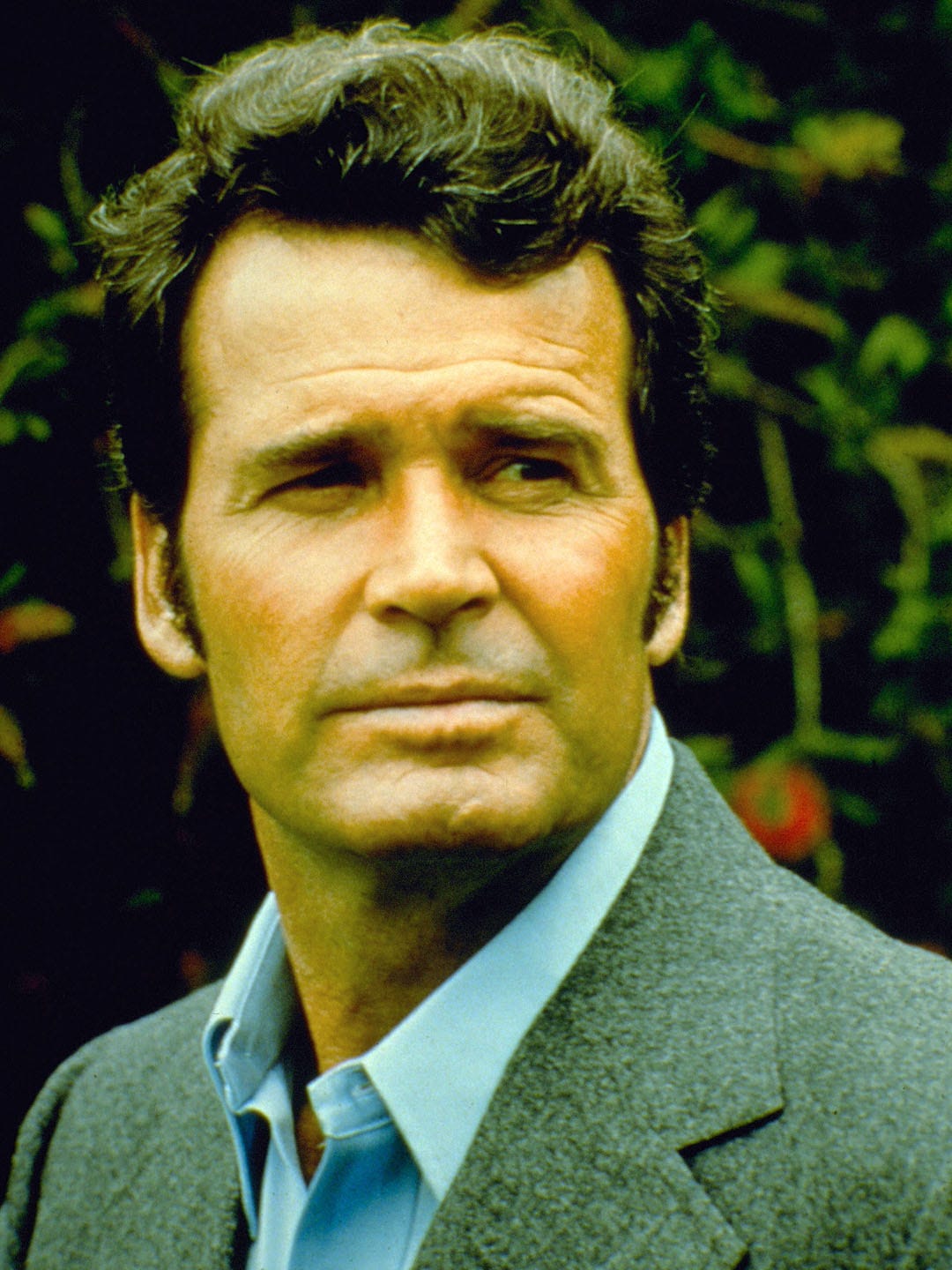 A headshot of the very handsome and debonnaire James Garner, in his role as Jim Rockford. He is squinting in a manly way and looking over to his left.