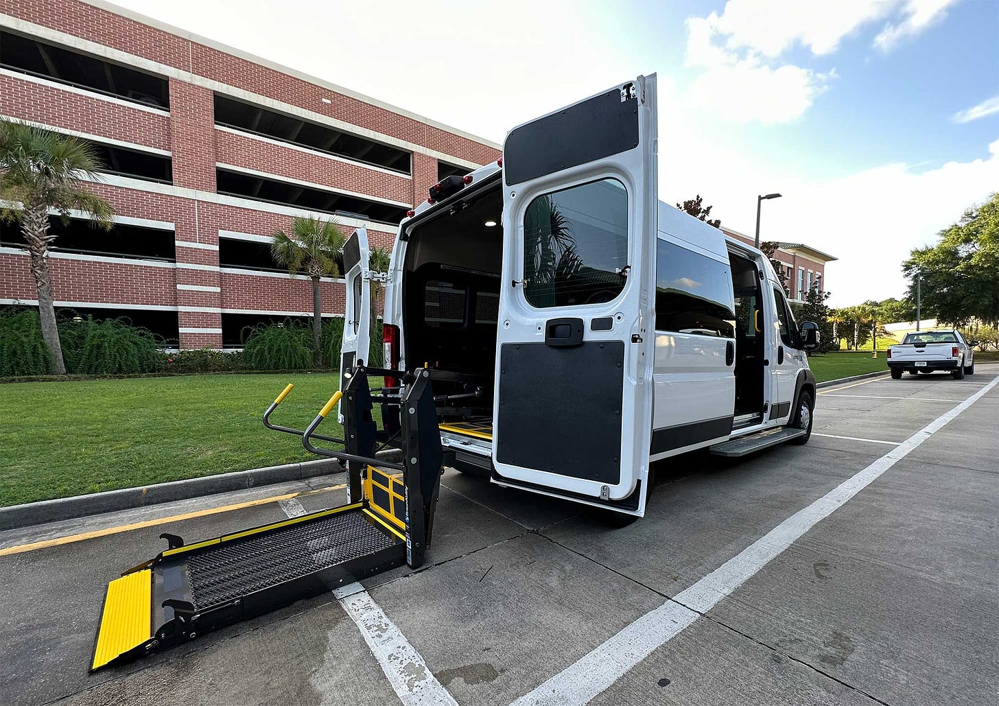 Wheelchair accessible van with lift extended parked in front of a parking garage at Savannah Airport.