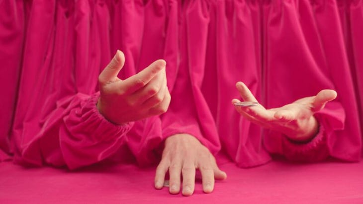 Three hands, poking out from a pink three-sleeved garment