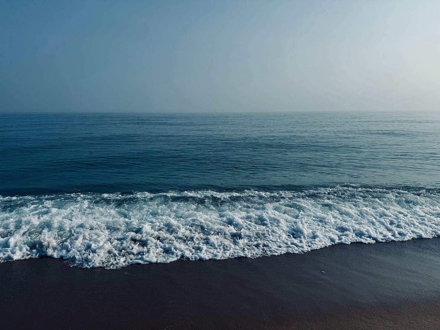 waves breaking on a sandy beach and calm ocean in the background