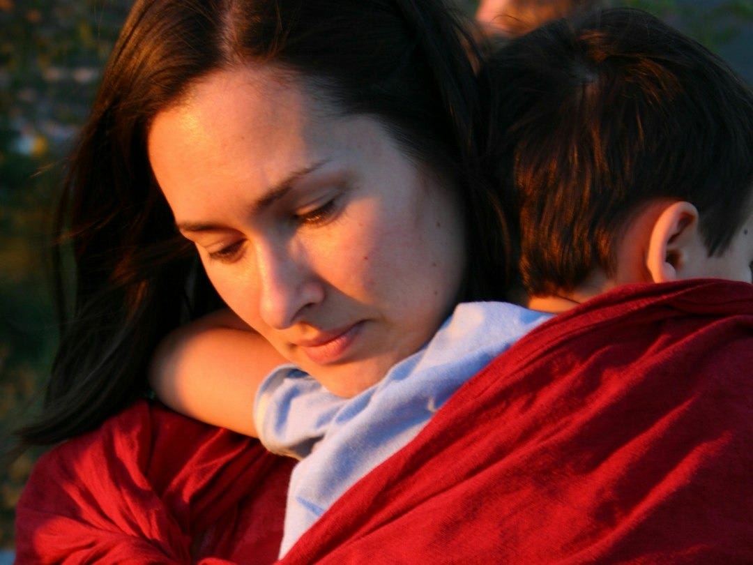 a woman holding a child wrapped in a red blanket