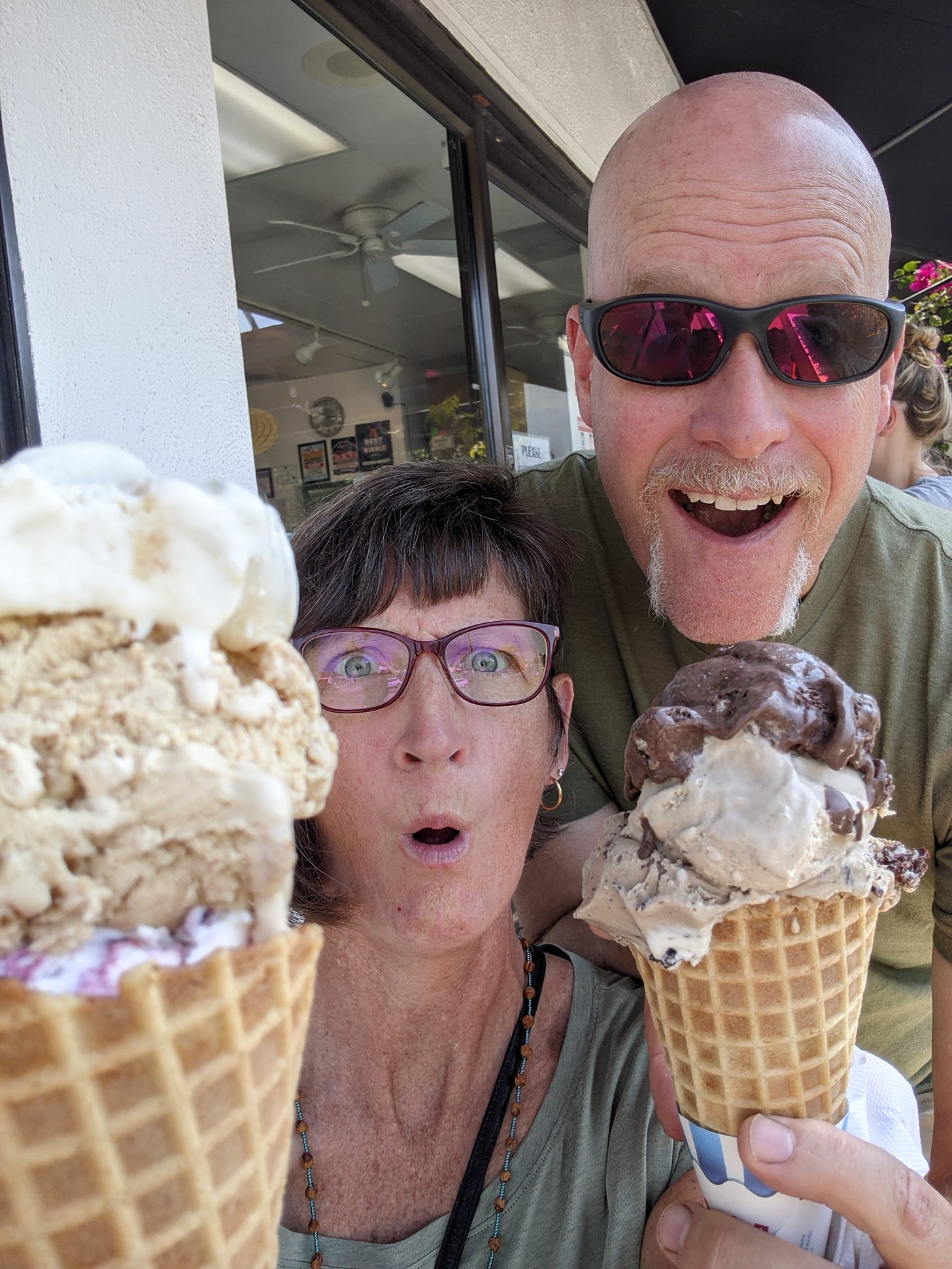 Two people with shocked looks on their faces, holding very large ice cream cones