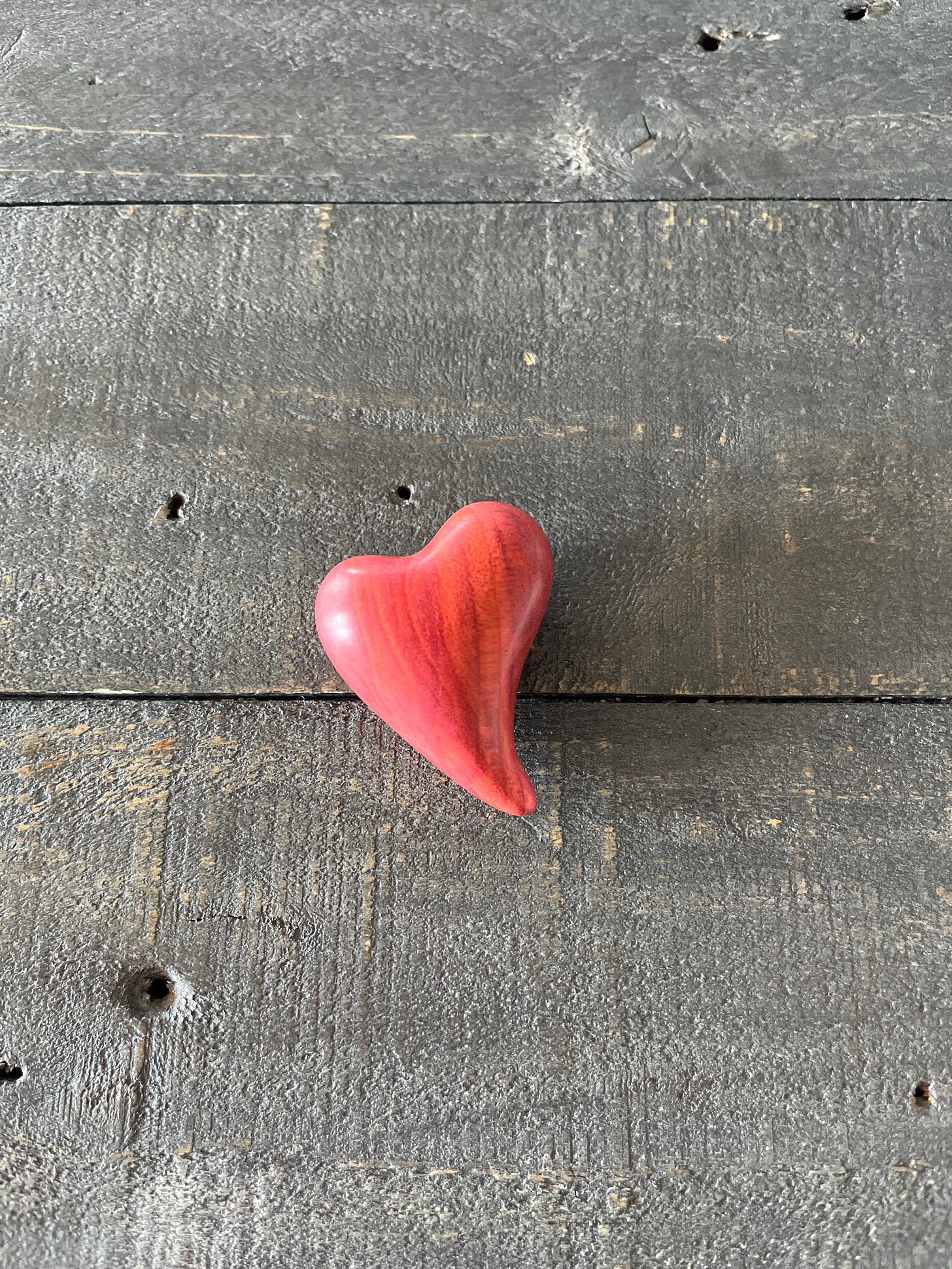 small wooden heart carved of rosewood, on a table made of gray driftwood