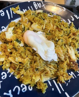 Kedgeree. It's a bowl of rice, coloured yellowy brown, with pieces of white fish and onion. There is a poached egg on top.