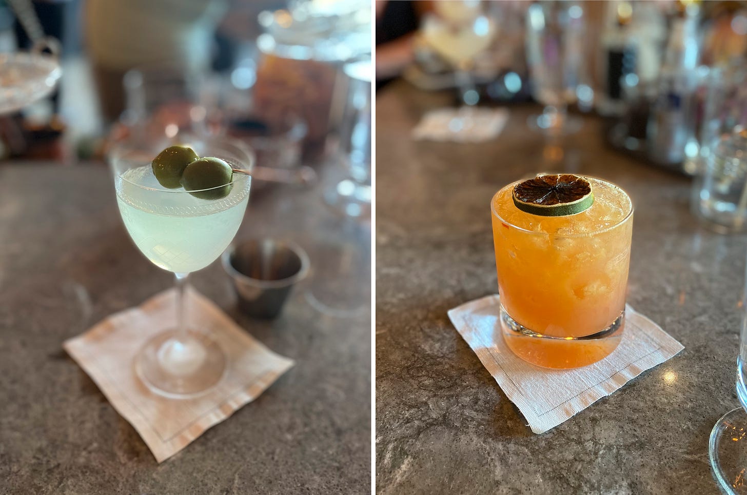 Left image: a dirty martini in a Nick-and-Nora glass with etched designs, two green olives on a metal toothpick across the top. Right image: a yellow-orange cocktail in a rocks glass over crushed ice, with a dried lime resting on top. Both sit on square, rustic canvas napkins.