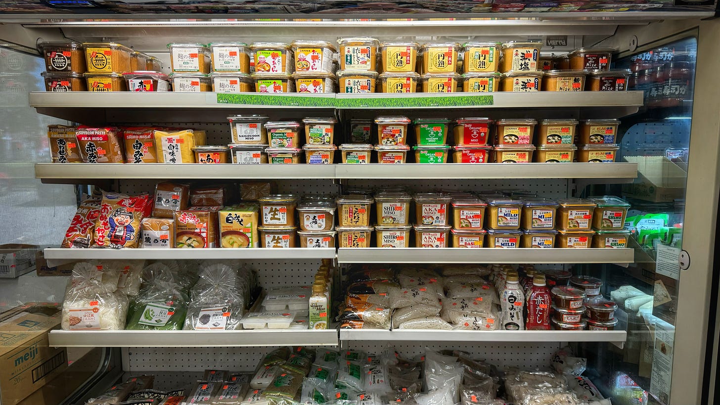 A display cooler at Heisei Mart stocked with over twenty types of miso, plus other refrigerated products