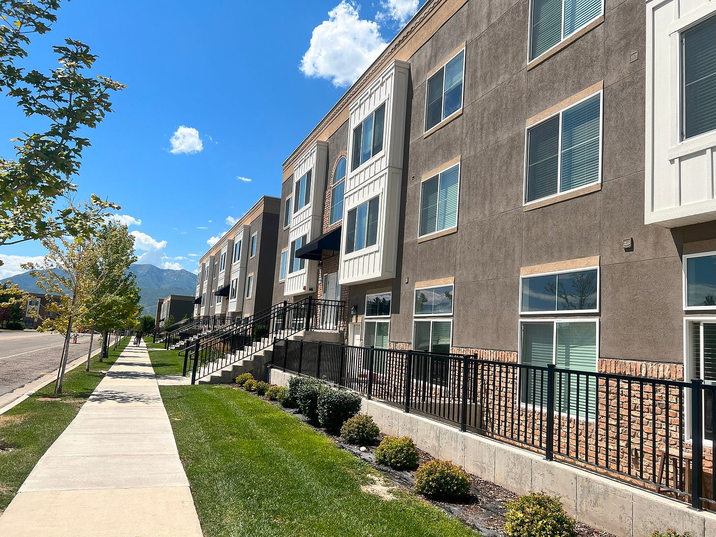 The view along the front of a three-story apartment building.