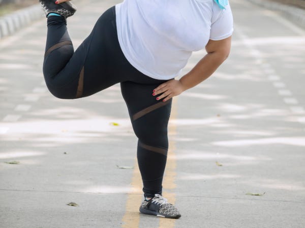 Pair of black-clad leggings on a large-bodied person stretching