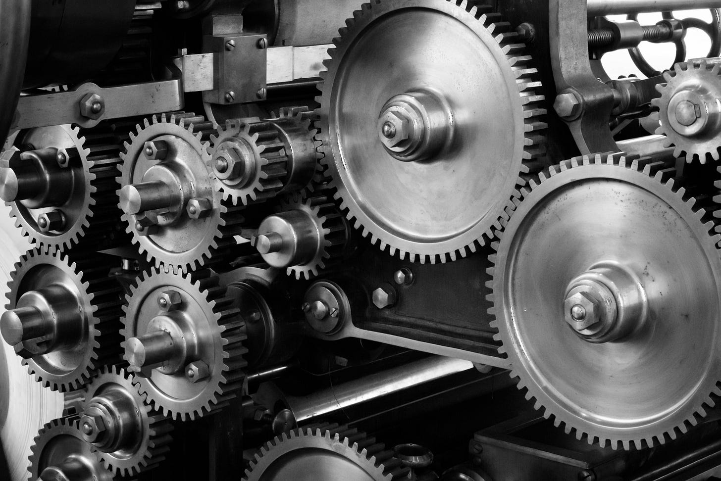 a black and white photo of a bunch of gears that seem to be part of a machine of some kind. it is unclear from the photo what kind of machine it is or what its purpose or function is.