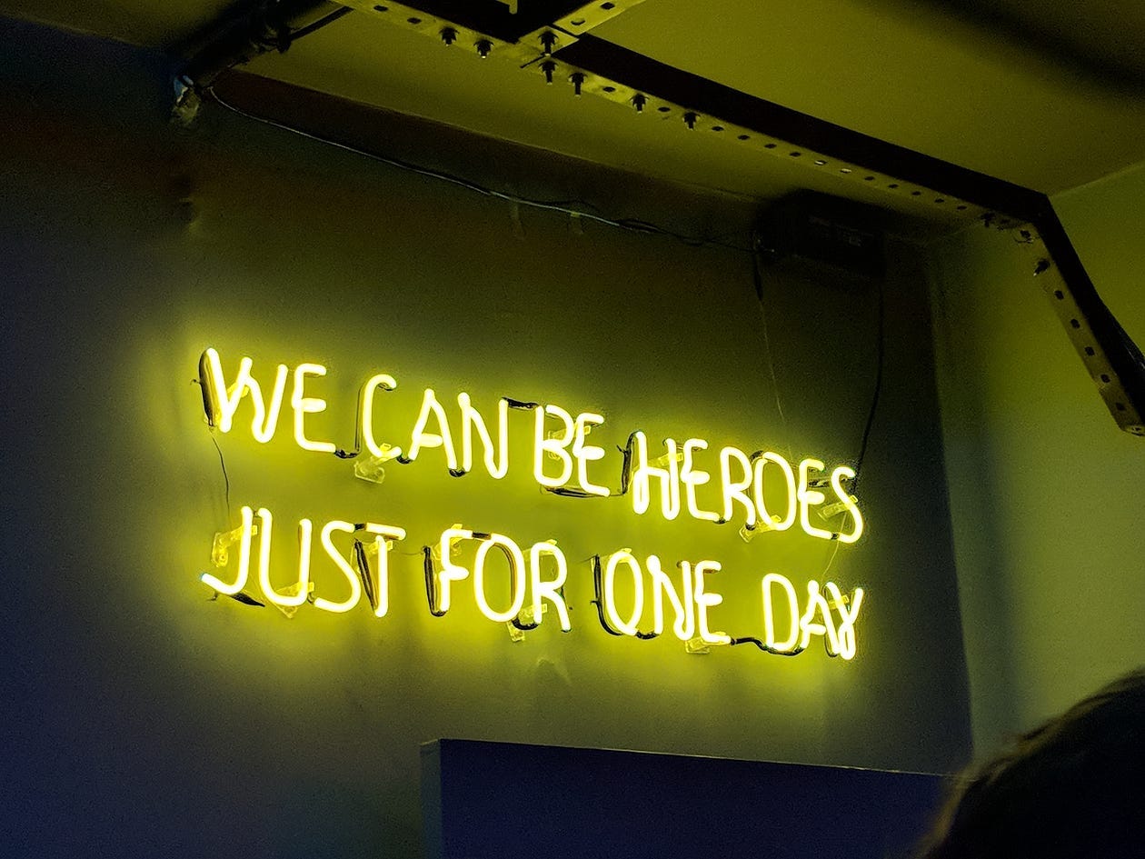 neon sign of the lyrics “we can be heroes just for one day”
