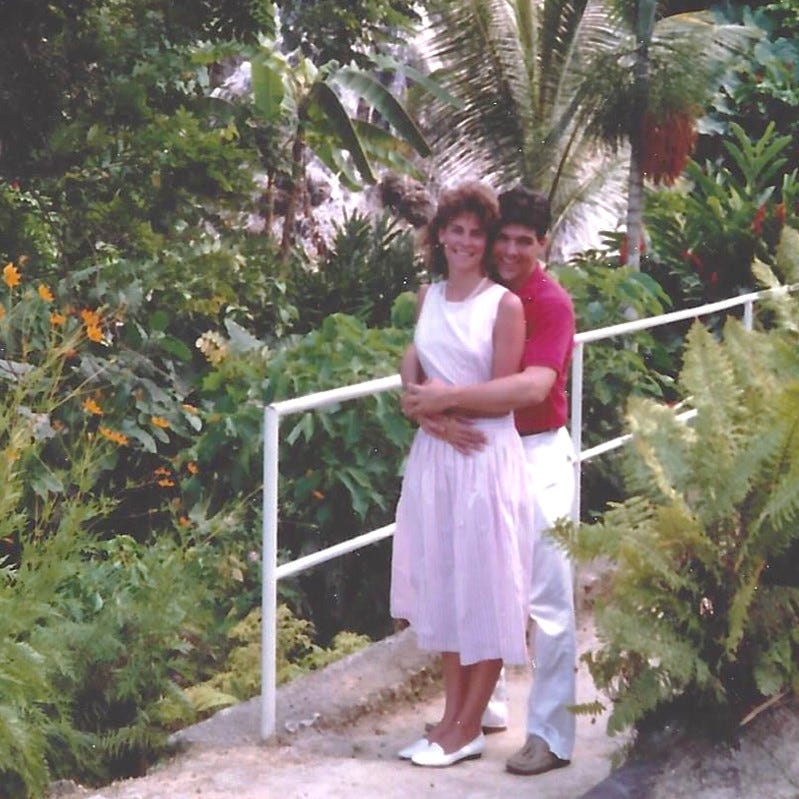 Smiling honeymooners embrace in a lush tropical garden