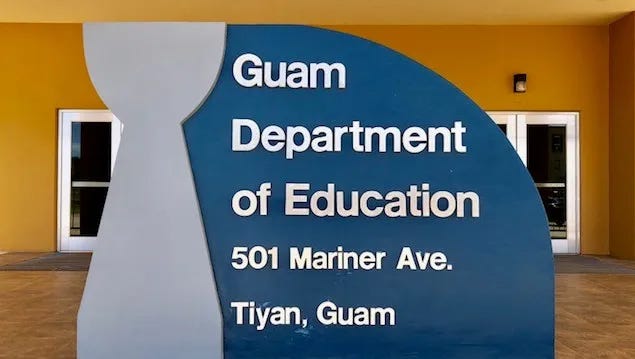 This color photograph shows the Guam Department of Education's official logo, set in a large stone mural in front of its central office. This color photograph shows the Guam Department of Education's official logo, set in a large stone mural in front of its central office.