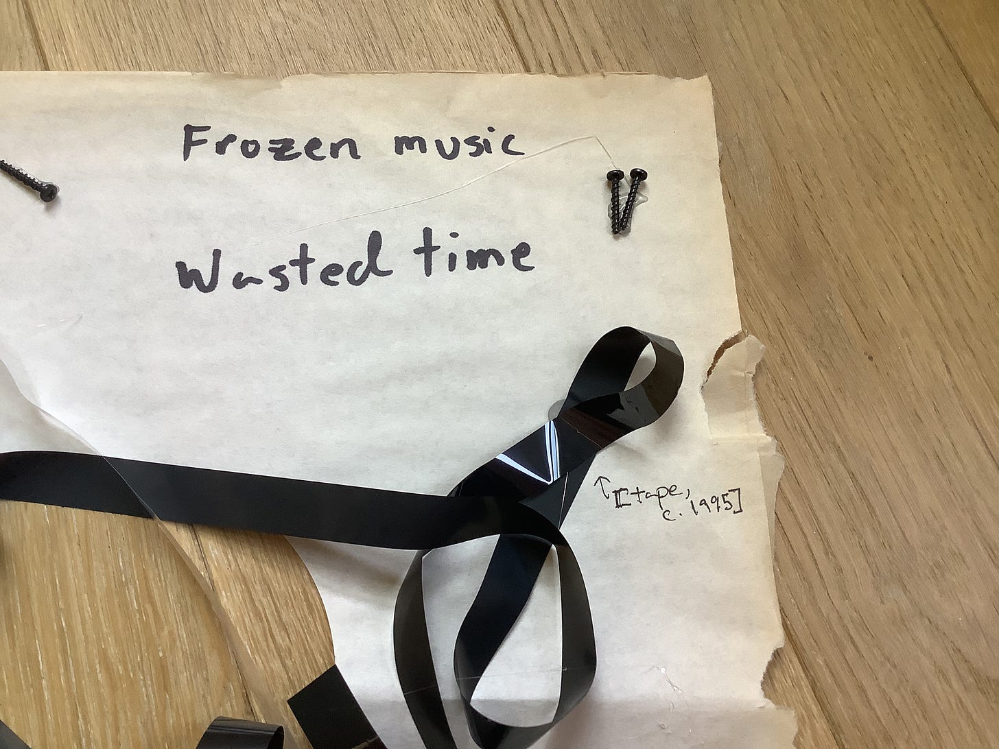 Detail with magnetic tape, screws, and the text “Frozen music / wasted time” plus an arrow marking “[tape, c. 1995]”