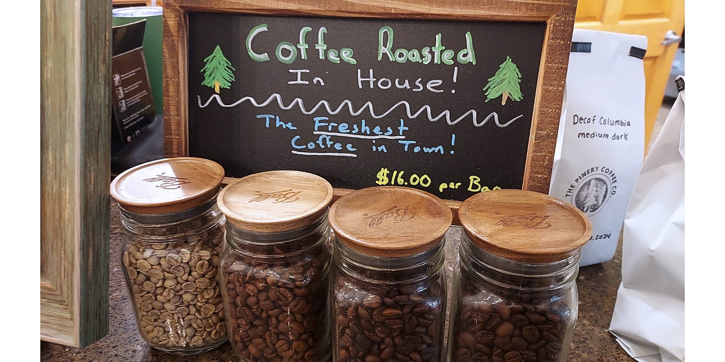 A close up of roasted coffee beans in a glass jars with wooden lids. Each jar features coffee beans roasted to an increasing level of darkness from left to right.