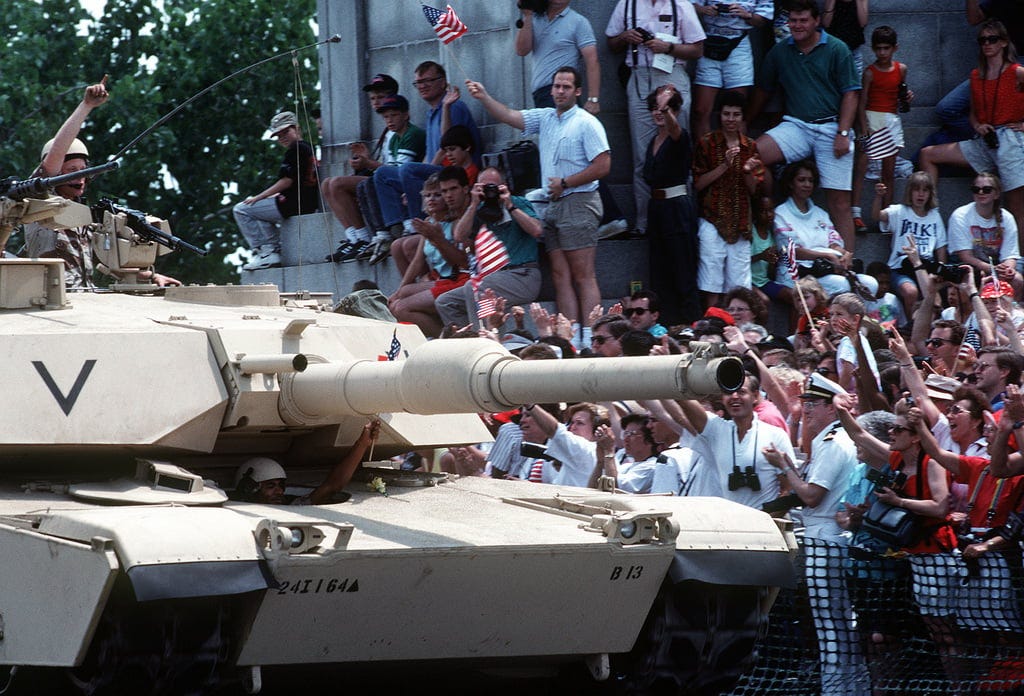 A color photo of a tan colored M-1 Abrams tank in the national Desert Storm victory parade. The tank is on the street in DC with the forward right front quadrant A color photo of a tan colored M-1 Abrams tank in the national Desert Storm victory parade. The tank is on the street in DC with the forward right front quadrant