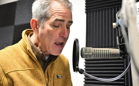 Boyd Huppert speaks into a microphone in a studio.