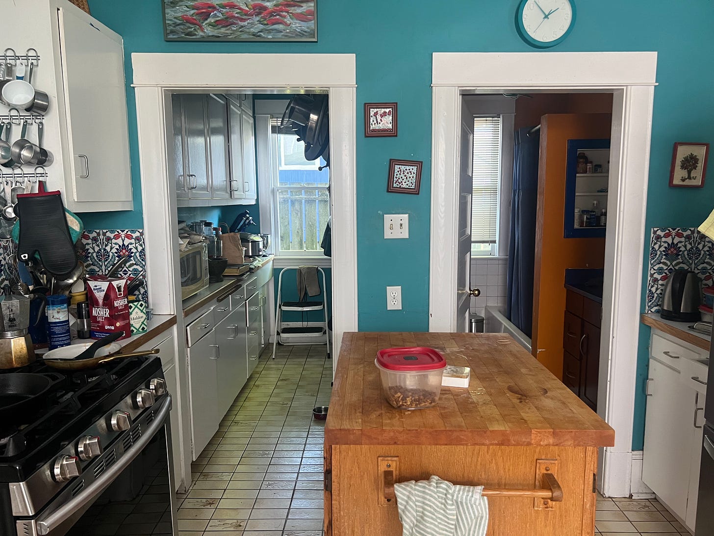 Kitchen with sea green coloured walls and wooden island in the centre.