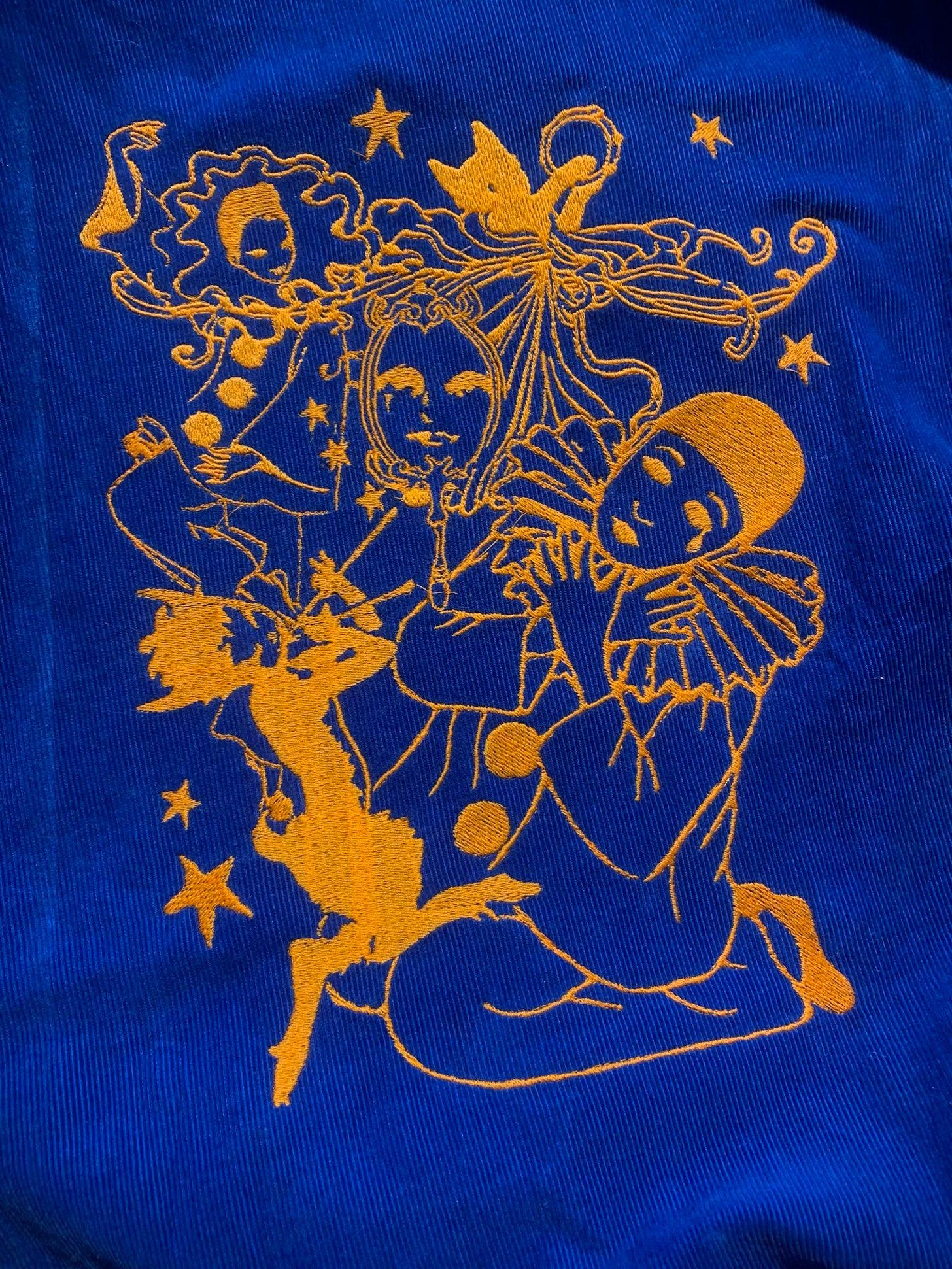 “On the Pisces Moon,” an embroidery I finished for my Fibers Residency in early March!  Bright orange stitching of a large sad pierrot clown holding themself, who is surrounded by a small satyr playing a pan flute, a happy dancing version of the pierrot clown, a cat in a flowing garment playing the tambourine, and several stars.