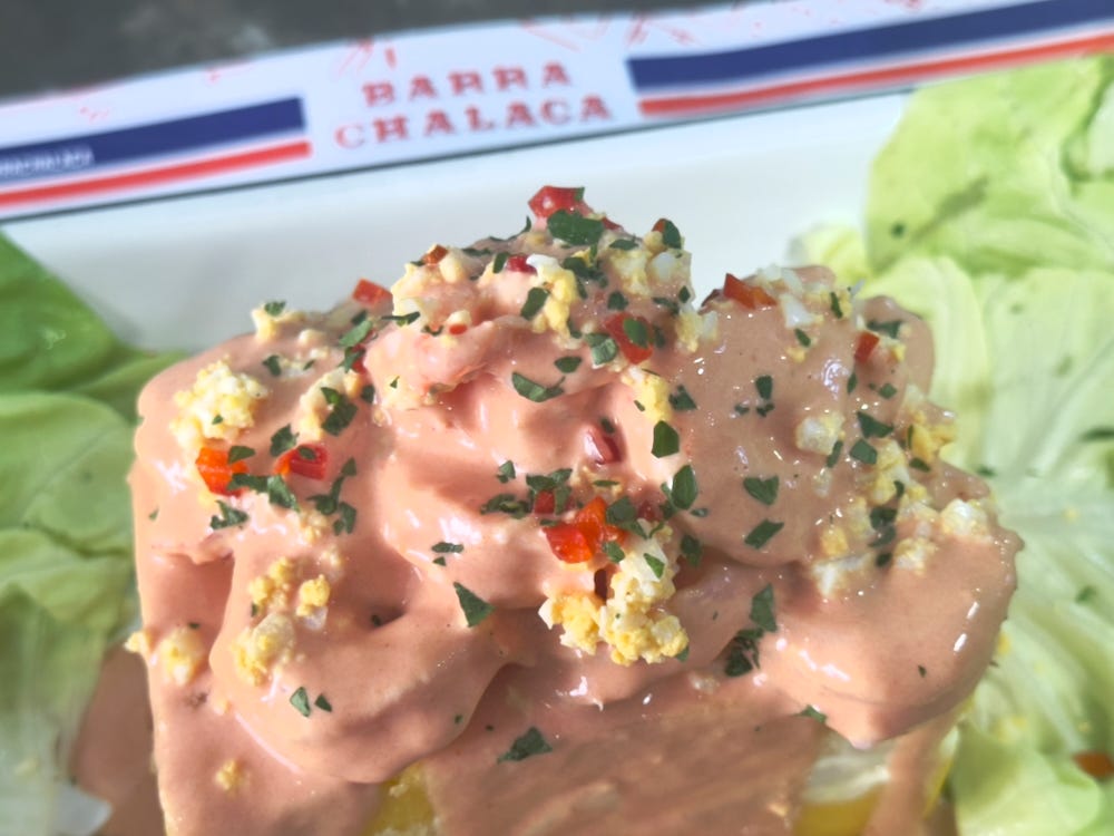 Pink causa topped with shrimp and egg and drenched in pink golf sauce