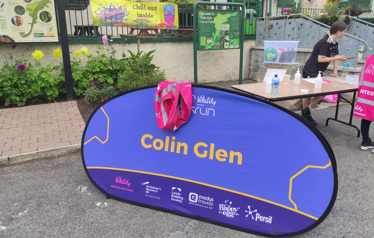 Large sign by the cafe says 'Colin Glen', yellow letters on blue background