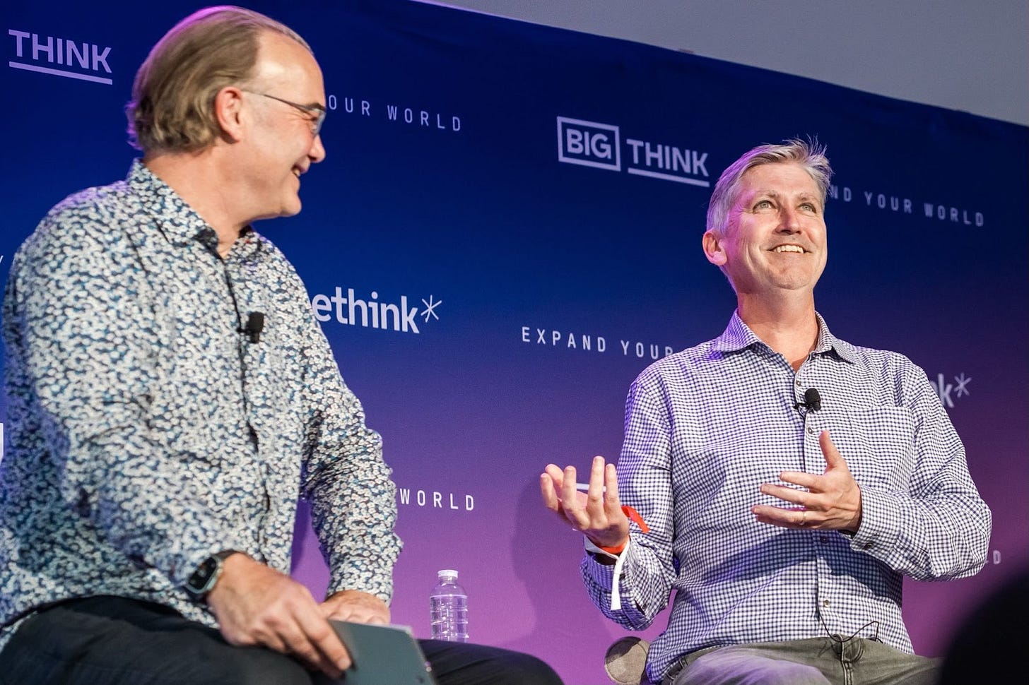 Two men sit and talk on stage at a Big Think event, one holding a notebook and the other gesturing with his hand. Two men sit and talk on stage at a Big Think event, one holding a notebook and the other gesturing with his hand.