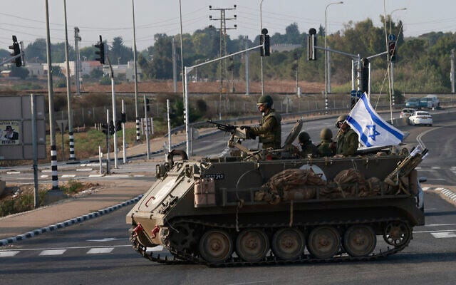 Israeli forces cross a main road in an armored personnel carrier (APC) as additional IDF troops are deployed near the southern city of Sderot following an assault by Hamas terrorists, October 8, 2023. (Menahem KAHANA / AFP)