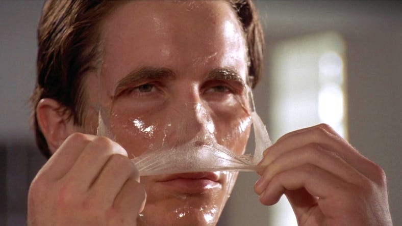 A scene from American Psycho showing Patrick Bateman peeling a translucent facial mask off his face, symbolizing a polished exterior hiding a lack of true self.