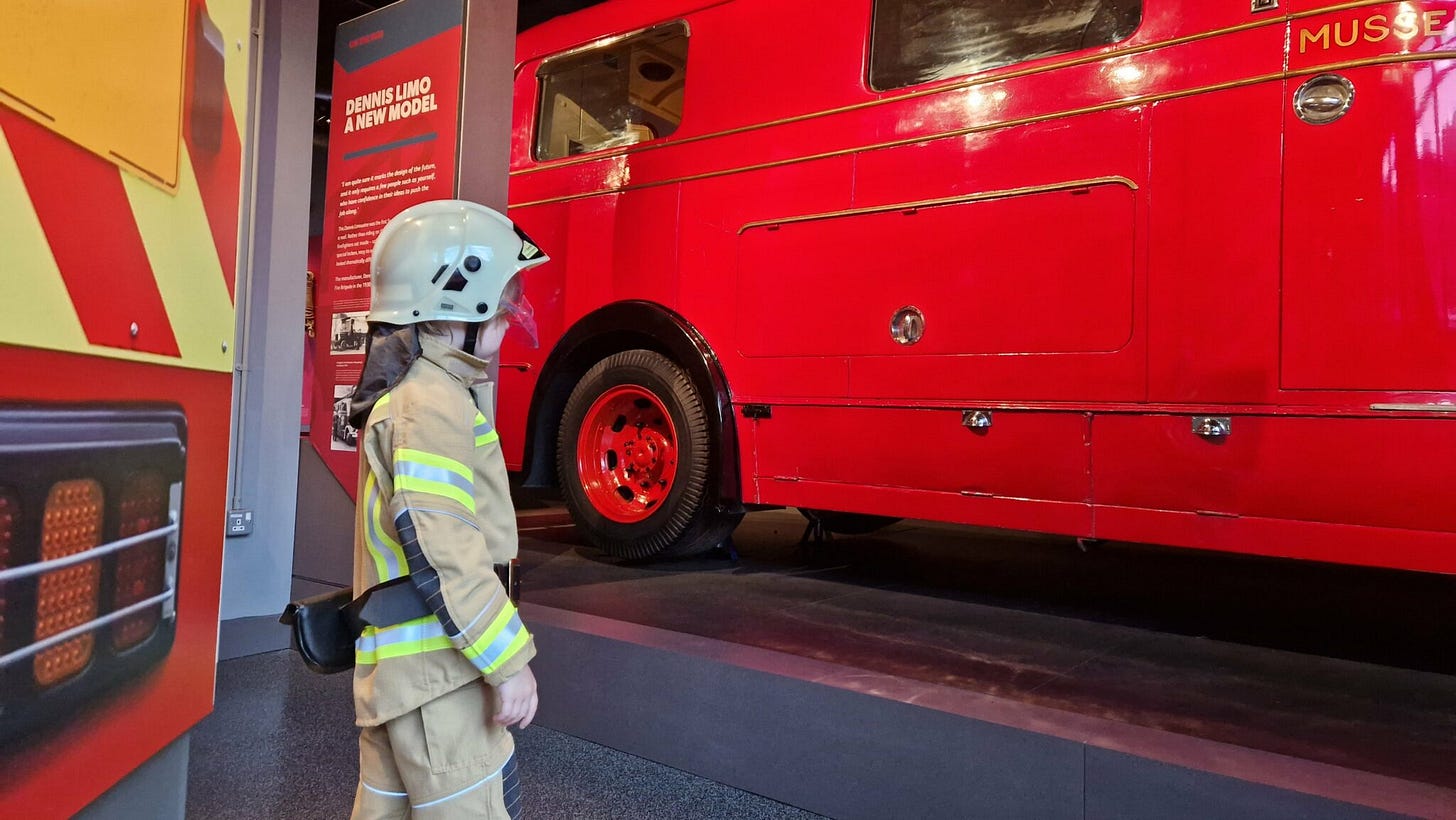 child dressed as a firefighter next to a vintage fire engine