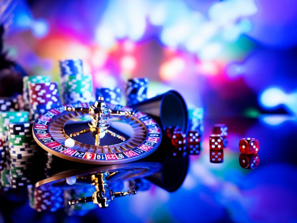 Stacks of poker chips, dice, and a mini roulette wheel among bright neon lights