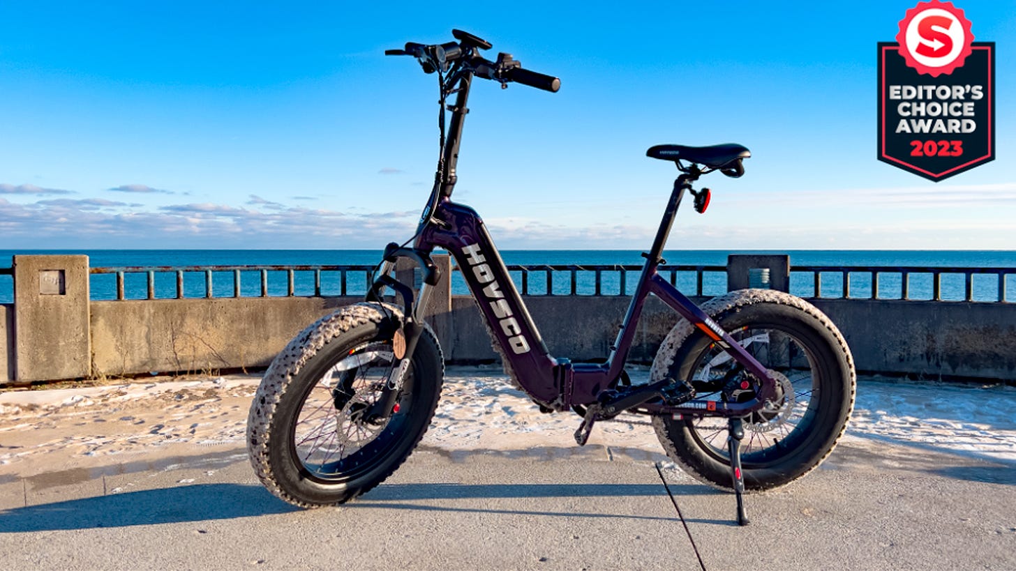 HovBeta folding electric fat bike in front of a body of water with The Shortcut Editors Choice award badge