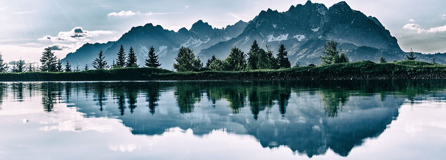 Trees and mountains reflected in a lake.