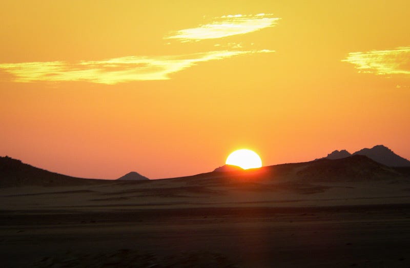 Amanecer con el sol saliendo por el horizonte en el desierto de Egipto