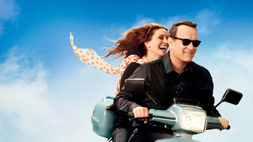 Movie promo photo of Mercedes, Mrs Tainot (Julia Roberts) riding on the back of the scooter with Larry Crowne (Tom Hanks)