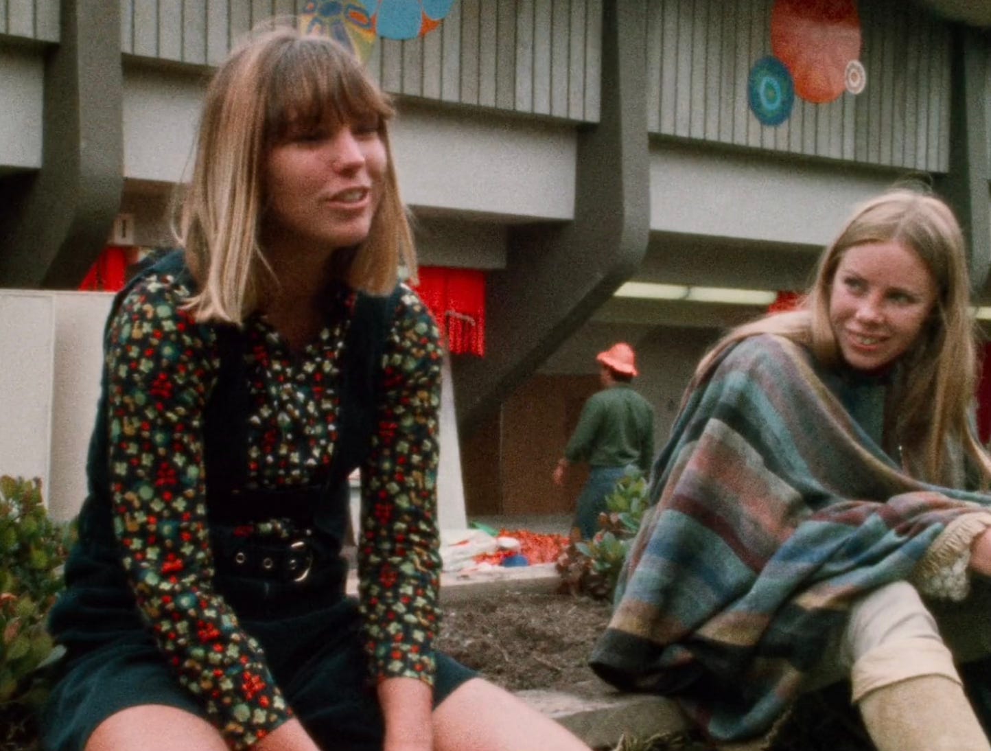 two young women sitting in a flower bed