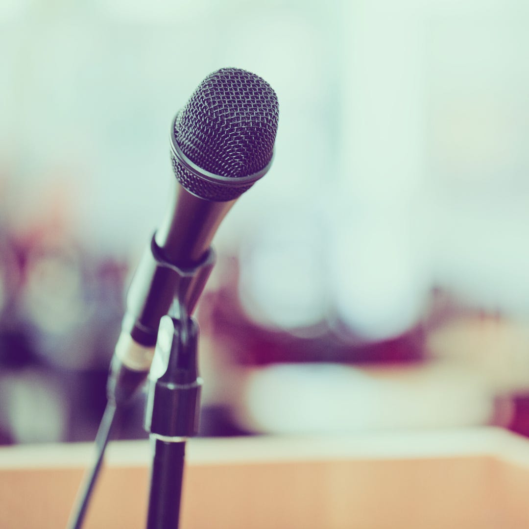 A photo of a microphone in front of an empty auditorium