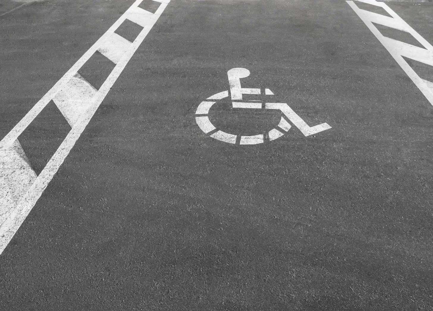 Wheelchair symbol stenciled on the pavement of an accessible parking space