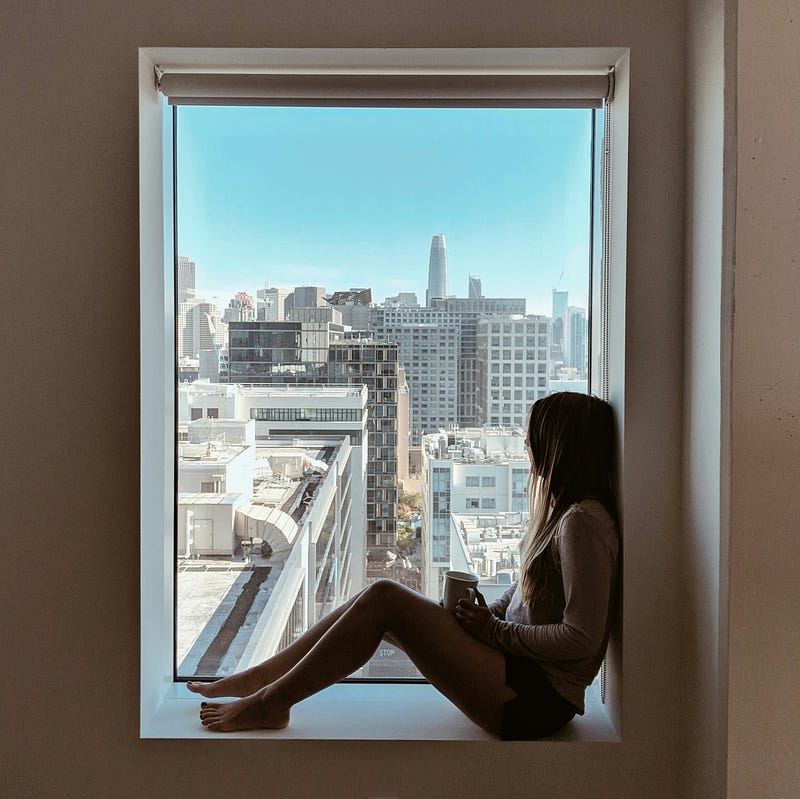 Woman looking out through window with tea cup in hand. Woman looking out through window with tea cup in hand.