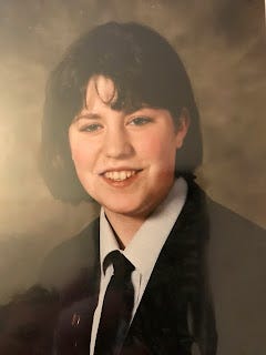 A school photo. It's me, Nicky Bond. I've got bobbed brown hair, with a fringe that's kinked against my will. I'm half smiling to the camera, I've got a navy blue blazer and tie, with a pale blue shirt, and my teeth are wonky AF.