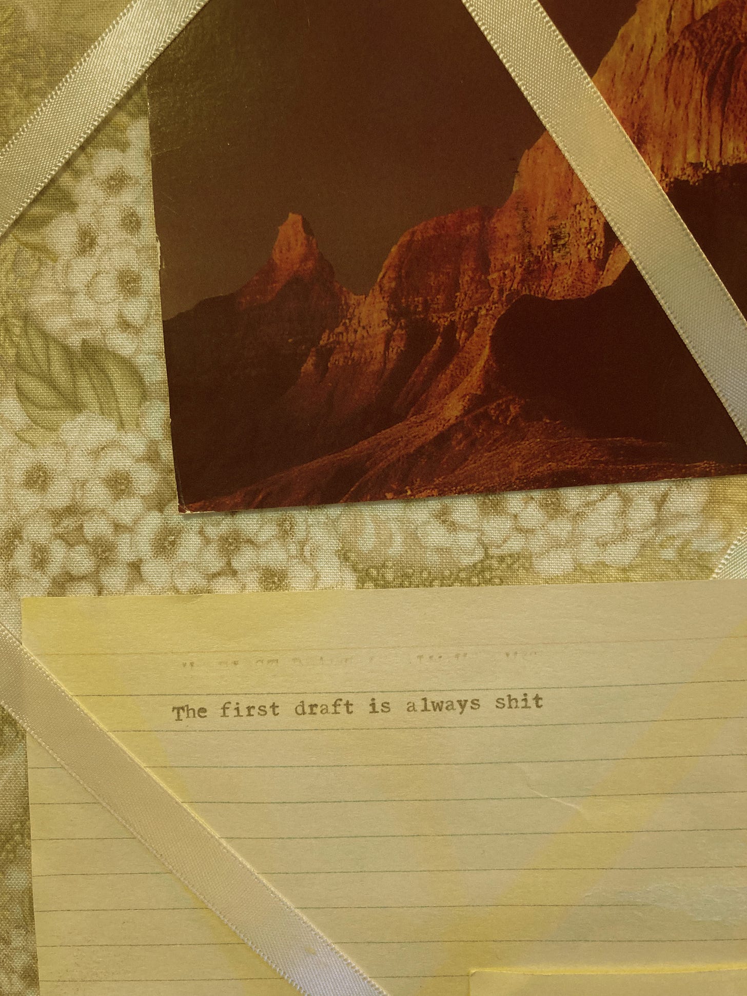 A postcard with bluffs and an index card with "the first draft is always shit" written on it
