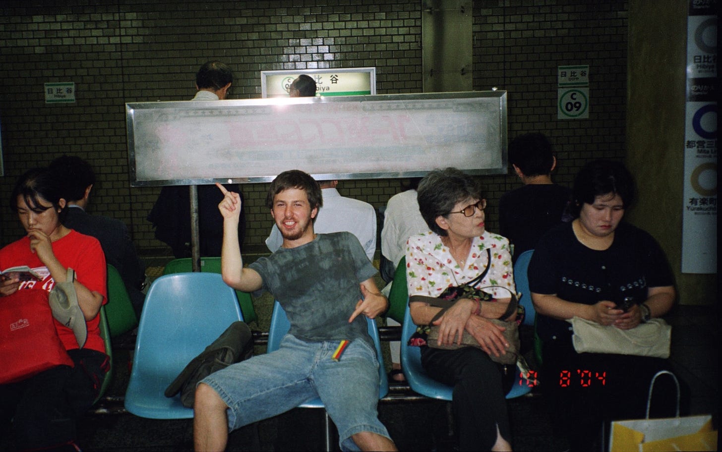Young boy sitting on a bench at a Tokyo subway station making hand gestures
