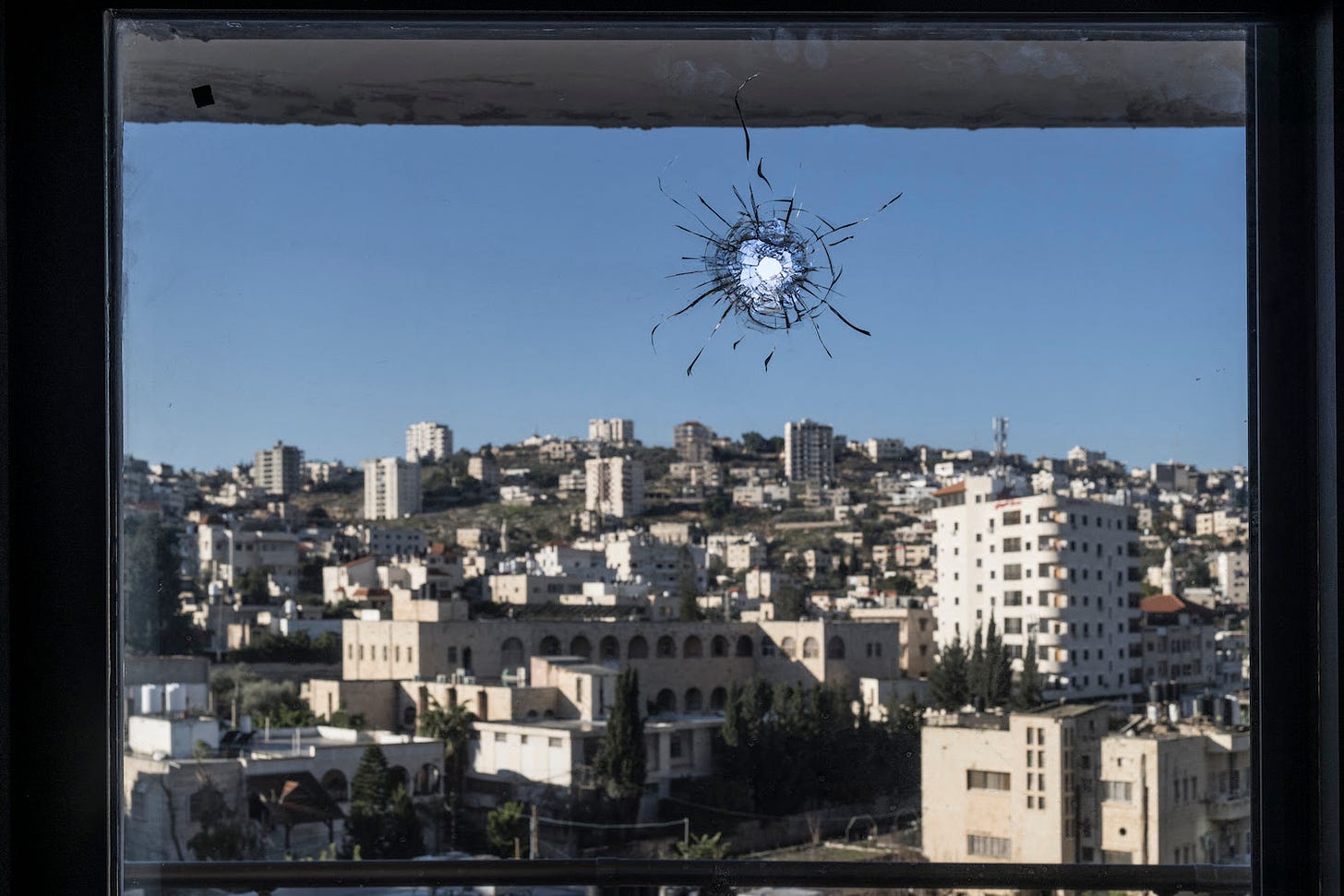 A hole from a stray bullet is seen in a window overlooking the West Bank city of Jenin.