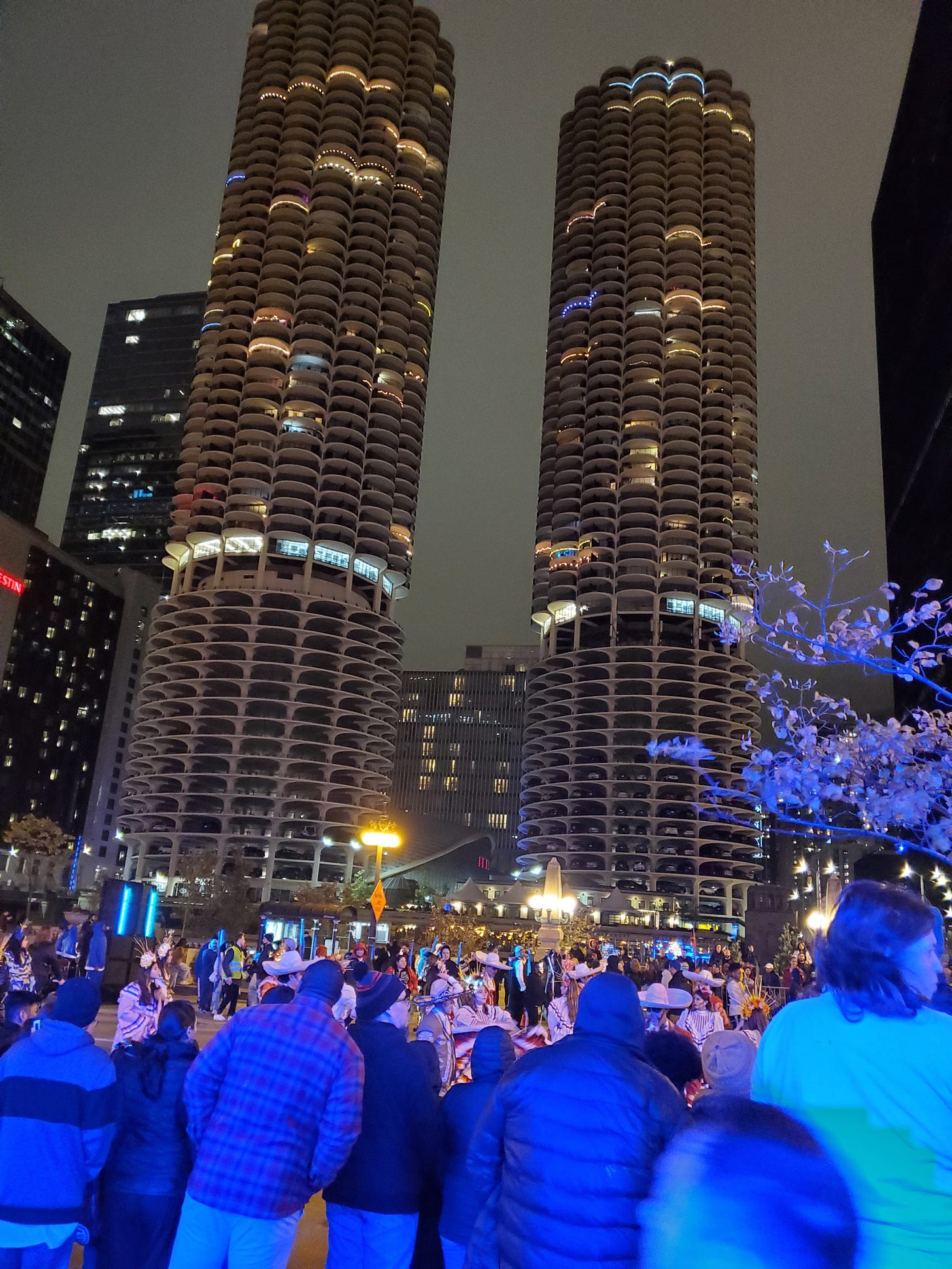Chicago's marina towers at night with a parade of costumed people heading to the right