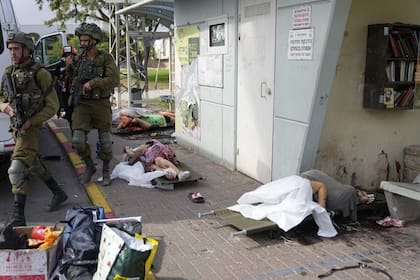 Soldados israelíes caminan junto a civiles asesinados por militantes palestinos en Sderot, Israe (AP Photo/Ohad Zwigenberg)