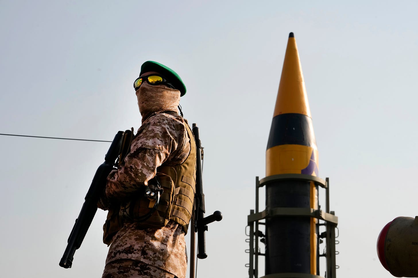 An Iranian Revolutionary Guard member stands guard in front of an Iranian missile