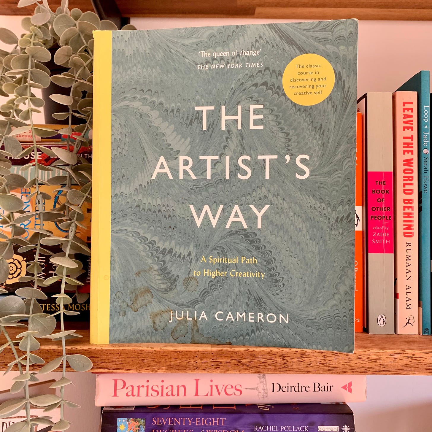 A paperback copy of The Artist's Way by Julia Cameron, face out on a bookshelf