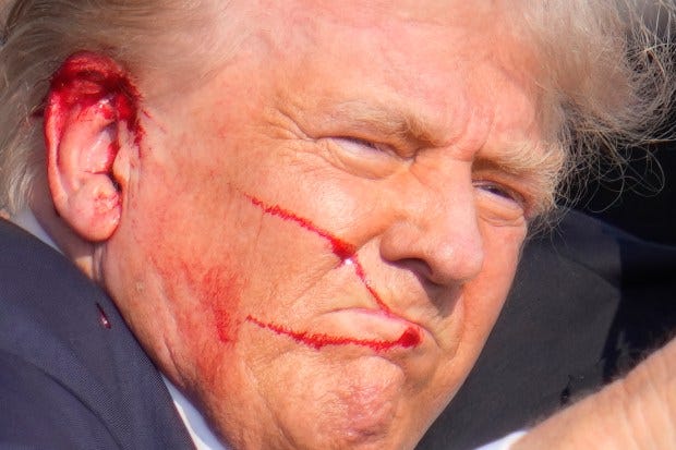 Republican presidential candidate former President Donald Trump gestures as he is surrounded by U.S. Secret Service agents as he is helped off the stage at a campaign rally in Butler, Pa., Saturday, July 13, 2024. (AP Photo/Gene J. Puskar)